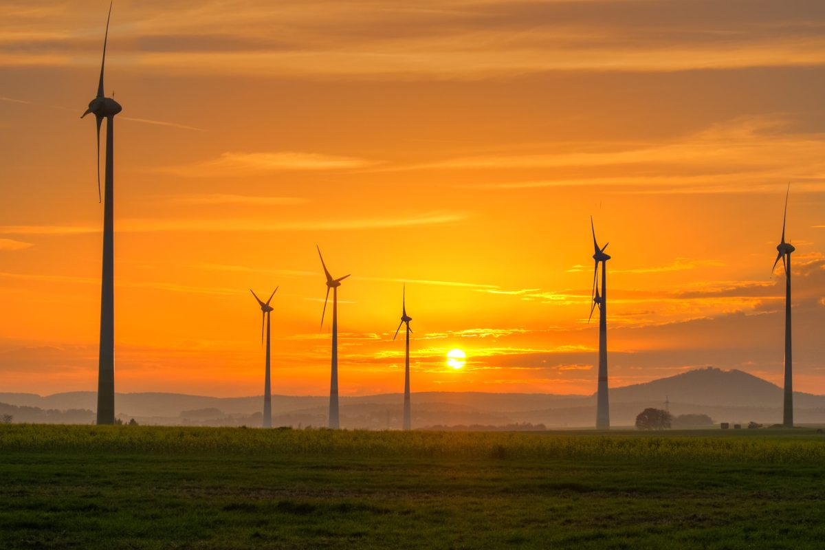 Windräder im Sonnenuntergang als Symbol für erneuerbare Energien und nachhaltige Heizlösungen von Nadira Bau AG.
